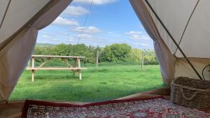 uma tenda com uma mesa de piquenique num campo em Home Farm Radnage Glamping Bell Tent 3, with Log Burner and Fire Pit em Radnage