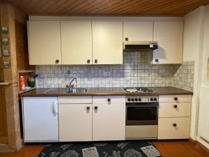 una cucina con armadietti bianchi e piano cottura di Casa Acacia con giardino ad Avegno