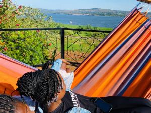 ein Kind, das in einer Hängematte mit Blick auf das Wasser liegt in der Unterkunft Home OnThe Nile Dorm in Jinja