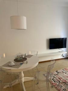 a white table and chairs in a room with a tv at Viale Pascoli Due in Cesenatico