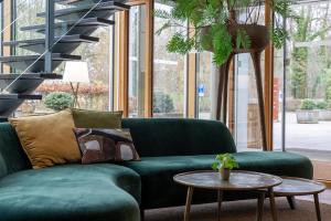 a green couch in a living room with a table at Hotel Mitland in Utrecht