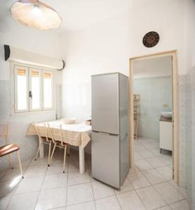 a kitchen with a table and a white refrigerator at Casa Tairsia in Torre Lapillo +50 photos
