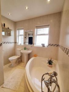 a bathroom with a tub and a toilet and a sink at - The Holly Tree House - in Bushmills