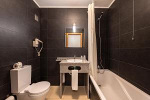uma casa de banho com um WC, um lavatório e uma banheira em Apartamentos Mirante da Rocha em Portimão