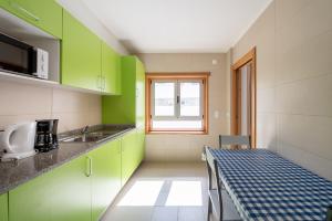 a small kitchen with green cabinets and a table at Apartamentos Mirante da Rocha in Portimão