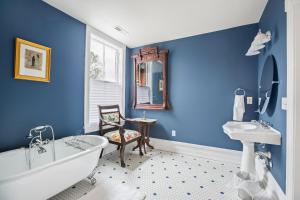 uma casa de banho com paredes azuis, uma banheira e uma cadeira. em Summit Street Inns em Winston-Salem