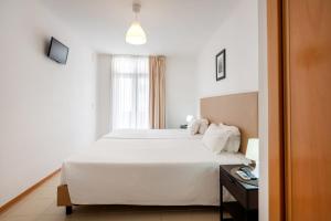 um quarto com uma cama branca e uma janela em Apartamentos Mirante da Rocha em Portimão