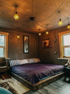 a bedroom with a bed with purple sheets and lights at Private Farm Jakuzzi Sauna in the forest in Talsi