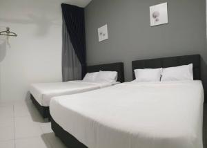 two beds in a hotel room with white sheets at Arcadia Homestay 7 @ Quintet in Tanah Rata