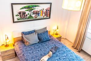 a bedroom with a blue bed and a picture on the wall at Thome Ego Flat in Cluj-Napoca