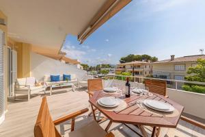 eine Terrasse mit einem Holztisch und Stühlen auf dem Balkon in der Unterkunft Bon Estar Apartment in Port d'Alcúdia