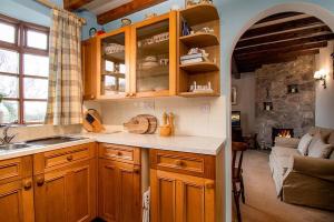 a kitchen with wooden cabinets and a living room at Tyddyn Crythor in Llangadwaladr