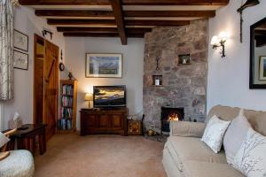 a living room with a couch and a fireplace at Tyddyn Crythor in Llangadwaladr