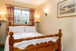 a bedroom with a wooden bed and a window at Tyddyn Crythor in Llangadwaladr