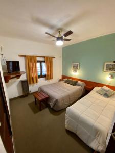 a bedroom with two beds and a ceiling fan at Hotel Samay Huasi in Villa General Belgrano