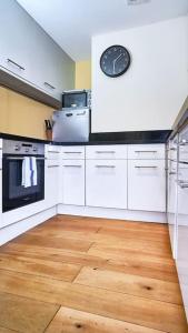 a kitchen with white cabinets and a clock on the wall at Stylish London Bridge Apartment in London