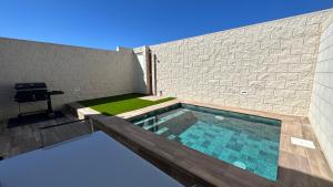 a swimming pool in front of a brick wall at Huellas de la Mancha in Burguillos de Toledo