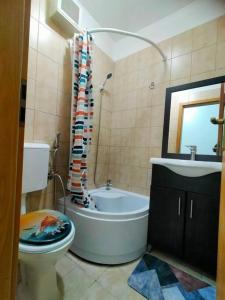 a bathroom with a tub and a toilet and a sink at Lake view luxury apartment in Bucharest