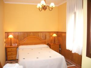 1 dormitorio con 1 cama, 2 lámparas y ventana en Apartments Aurora, en La Robellada de Onis