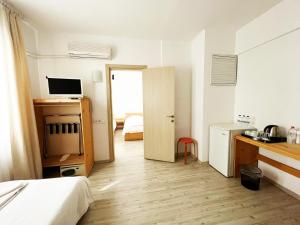 a room with a bed and a desk and a kitchen at Zephyros City Otel in Datca