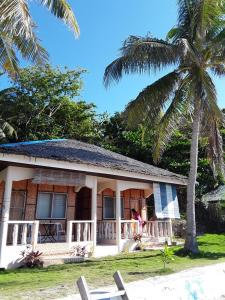 a house on the beach with a palm tree at Islanders Paradise Beach in Larena
