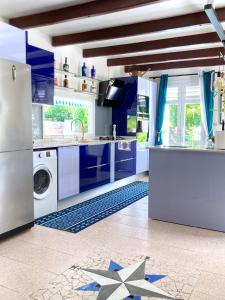 a kitchen with blue cabinets and a washing machine at Villa La Roserie in Ducos