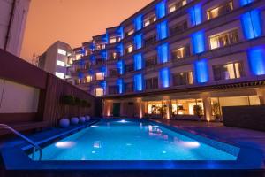 a hotel with a swimming pool in front of a building at Pharos Hotels in Chennai