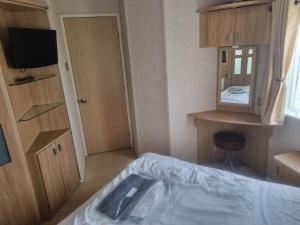 a room with a bed and a tv and a mirror at 6 BERTH DELUXE ML7 ON THE GOLDEN PALM in Chapel Saint Leonards +16 photos
