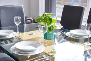 a table with plates and glasses and a plant on it at Pleasure Holiday Apartments in Blackpool