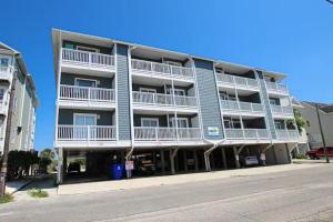a blue apartment building with white balconies and a street at Souls in the Sand in Carolina Beach