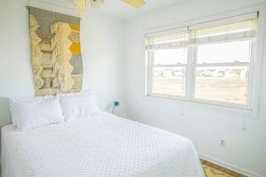 een witte slaapkamer met een bed en een raam bij Boho at the Beach in Carolina Beach