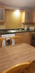 uma cozinha com uma mesa de madeira com cadeiras e um lavatório em 2 bed caravan parkdean saltfleet near mablethorpe em Saltfleet