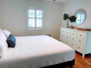 a bedroom with a white bed with a dresser and a mirror at Vitamin Sea in Carolina Beach