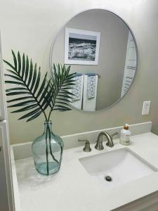 a vase sitting on a bathroom sink with a mirror at Vitamin Sea in Carolina Beach