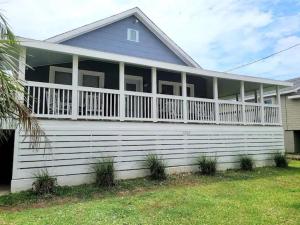 Cette maison dispose d'une grande terrasse couverte et d'une balustrade blanche. dans l'établissement House of Kai, à Carolina Beach