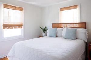 a white bedroom with a large white bed with blue pillows at House of Kai in Carolina Beach