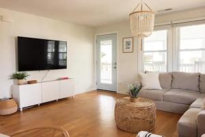 uma sala de estar com um sofá e uma televisão de ecrã plano em House of Kai em Carolina Beach