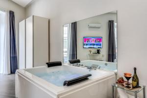 een grote witte badkamer met een bad en een tv bij Gallery Suite Naples in Napels