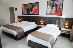 two beds in a hotel room with paintings on the wall at SAR-PER Hotel in Edirne
