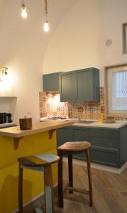 eine Küche mit grünen Schränken und 2 Hockern in der Unterkunft La Casetta di Zoe Apartment in Molfetta