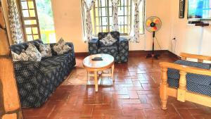 sala de estar con sofás negros y mesa en Keelan ace villas, en Kampala