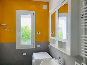 a bathroom with a toilet and a sink and two windows at Lupicante 56 Cesenatico in Cesenatico +60 photos