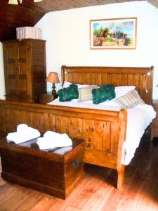 Authentic Irish Cottage, Rural Ballymascanlon : غرفة نوم بسرير خشبي عليها مخدات خضراء