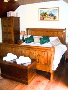 a bedroom with a wooden bed with green pillows on it at Authentic Irish Cottage, Rural Ballymascanlon in Ballymascanlan