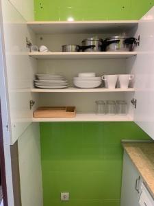 ベニドルムにあるAcuarium IIの緑の壁と白い棚が備わるキッチン(食器付)