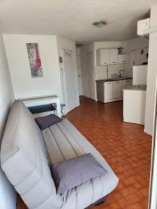 a living room with a white couch and a kitchen at Joli T2 Centre port résidence Quai d'Honneur in Cap d'Agde