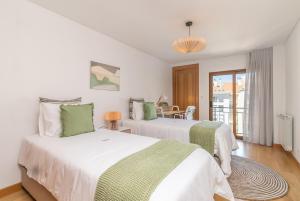 a bedroom with two beds with green and white sheets at Spacious and Chic Apartment with Lisbon, Sintra, or Beach at 15 min! in Amadora