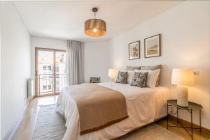 um quarto branco com uma cama e uma janela em Spacious and Chic Apartment with Lisbon, Sintra, or Beach at 15 min! na Amadora