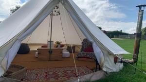 a white tent with a bed in a field at Home Farm Radnage Glamping Bell Tent 2, with Log Burner and Fire Pit in Radnage