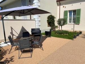 a table and chairs under an umbrella on a patio at Villino Micol camere a due passi dal mare in Marina di Carrara